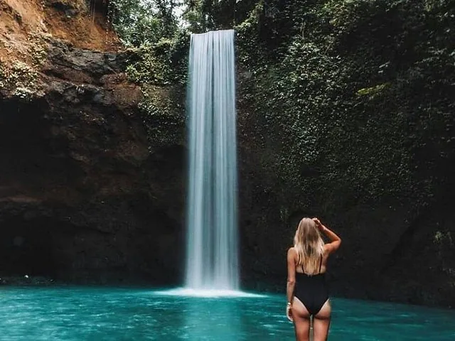 Woman in swimsuit standing near a picturesque waterfall and turquoise pool