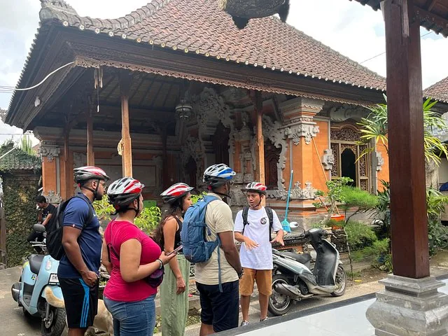 Group of cyclists listening to their guide outside a traditional Balinese building