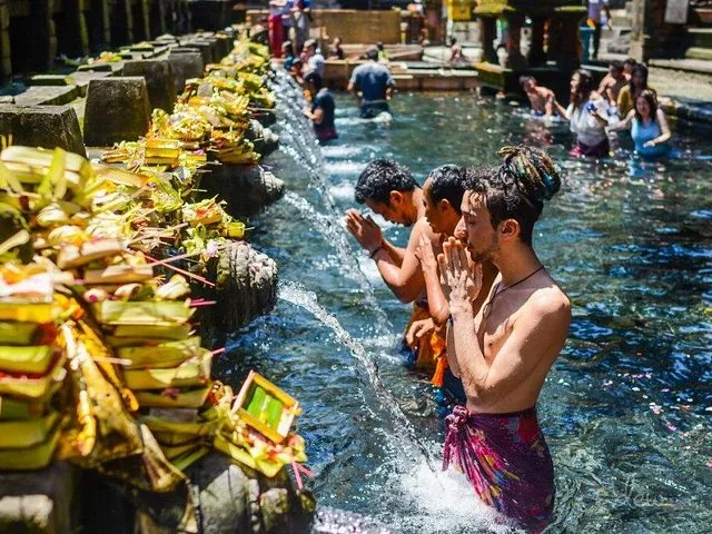 Men praying under water spouts during a purification ritual at a temple